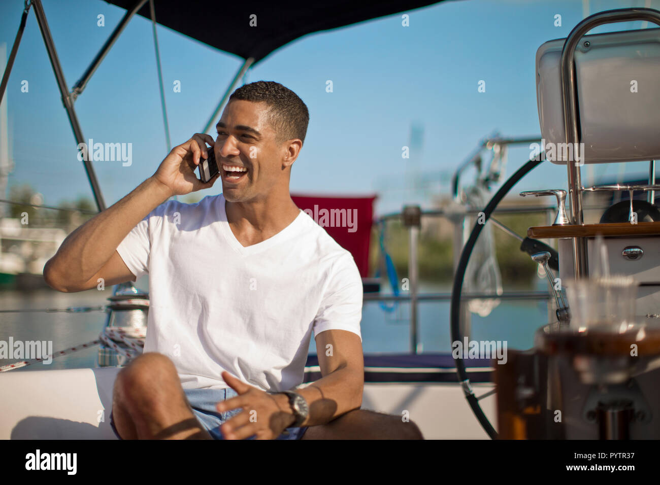 Lächelnden jungen Mann über sein Mobiltelefon auf einem Boot. Stockfoto