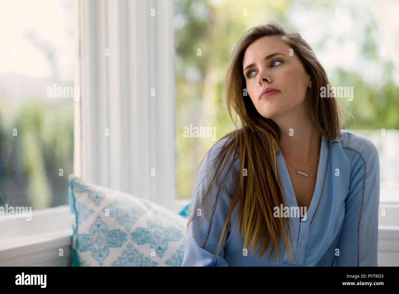 Junge Frau auf der Suche Fenster. Stockfoto