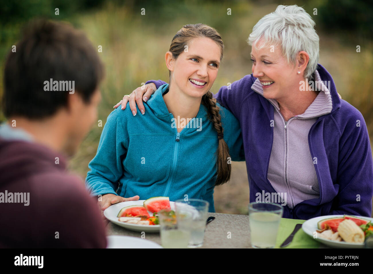 Zärtlich, reife Frau Aktien ein Picknick mit ihrer Tochter und ihrem Schwiegersohn am Strand. Stockfoto