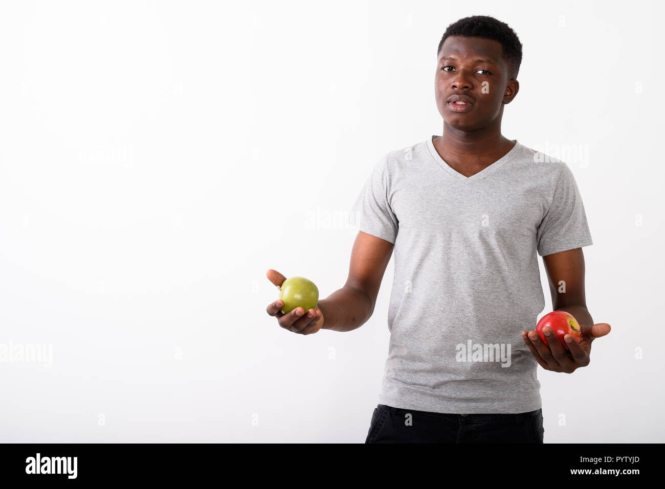 Studio shot von jungen schwarzen afrikanischen Mann hält roten Apfel und gre Stockfoto