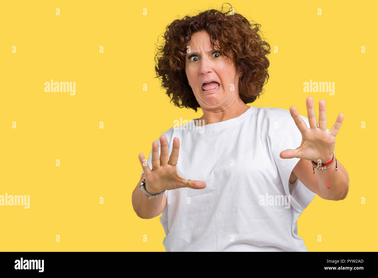 Schöne Mitte ager Senior Frau tragen weiße T-Shirt über isolierte Hintergrund Angst und Furcht Ausdruck stop Geste mit den Händen Angst, s Stockfoto