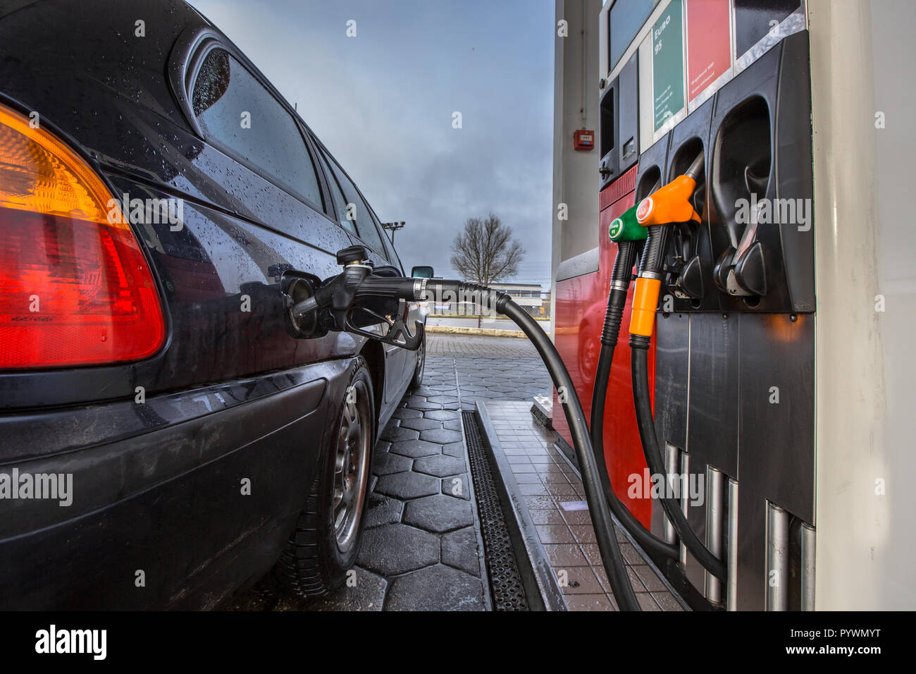 Gas Pumpe Füllen an einer Tankstelle Auto nah an einem verregneten Februar Tag mit dunklen Farben in den Niederlanden Stockfoto