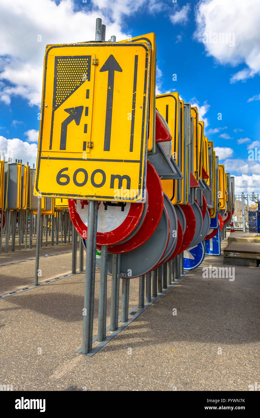 Gelbe Straße Verengung Zeichen unter anderen Zeilen von Verkehrszeichen warten in Straßenbauprojekte angestellt zu werden. Stockfoto