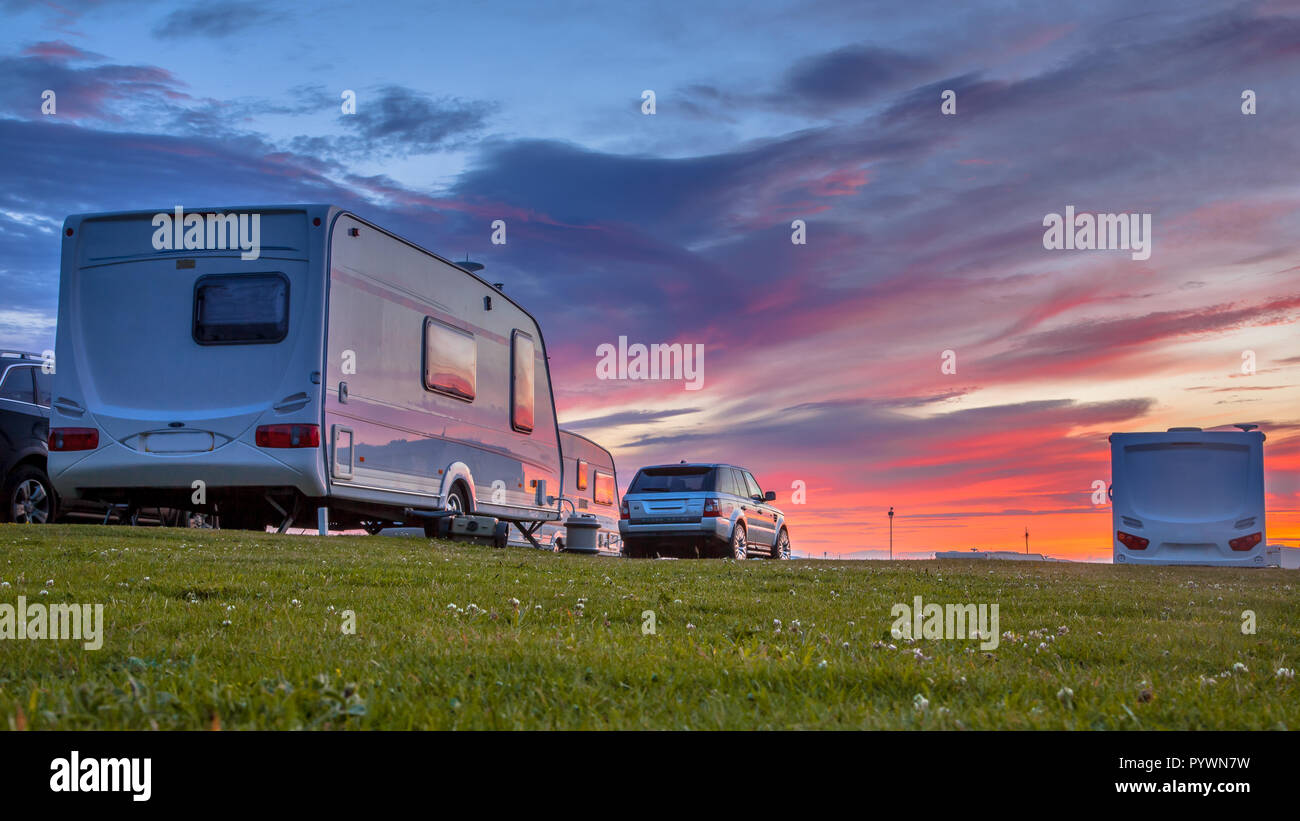 Wohnwagen und Autos auf einem grasbewachsenen Campingplatz im Sommer geparkt unter schönen Sonnenuntergang Stockfoto