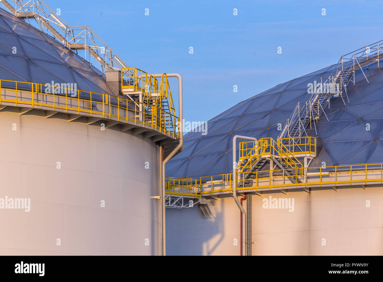 Moderne Öl Lagertanks mit Detail von Stufen und Treppen im industriellen Bereich am Hafen im warmen Abendlicht in den Niederlanden Stockfoto