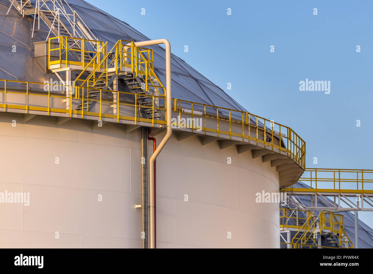 Moderne Big Oil storage Tanks mit Detail von Stufen und Treppen im industriellen Bereich am Hafen im warmen Abendlicht in den Niederlanden Stockfoto