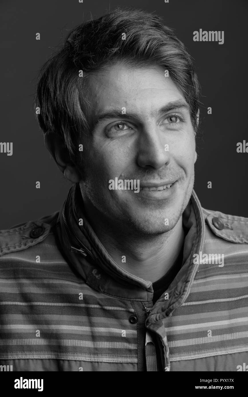 Schöner Mann gegen grauen Hintergrund in Schwarz und Weiß Stockfoto