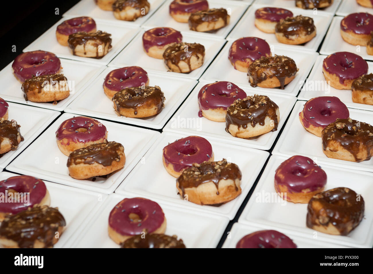 Mehrere Platten mit jeweils zwei frosted Donuts (Donuts). Stockfoto