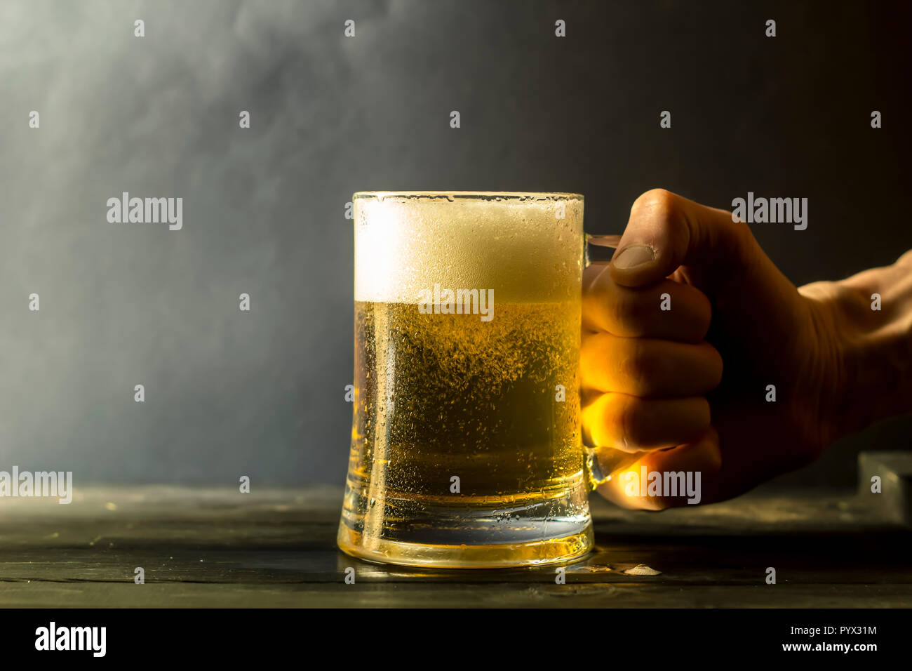 Eine Hand hält sie einen Becher frisches Bier. Stockfoto