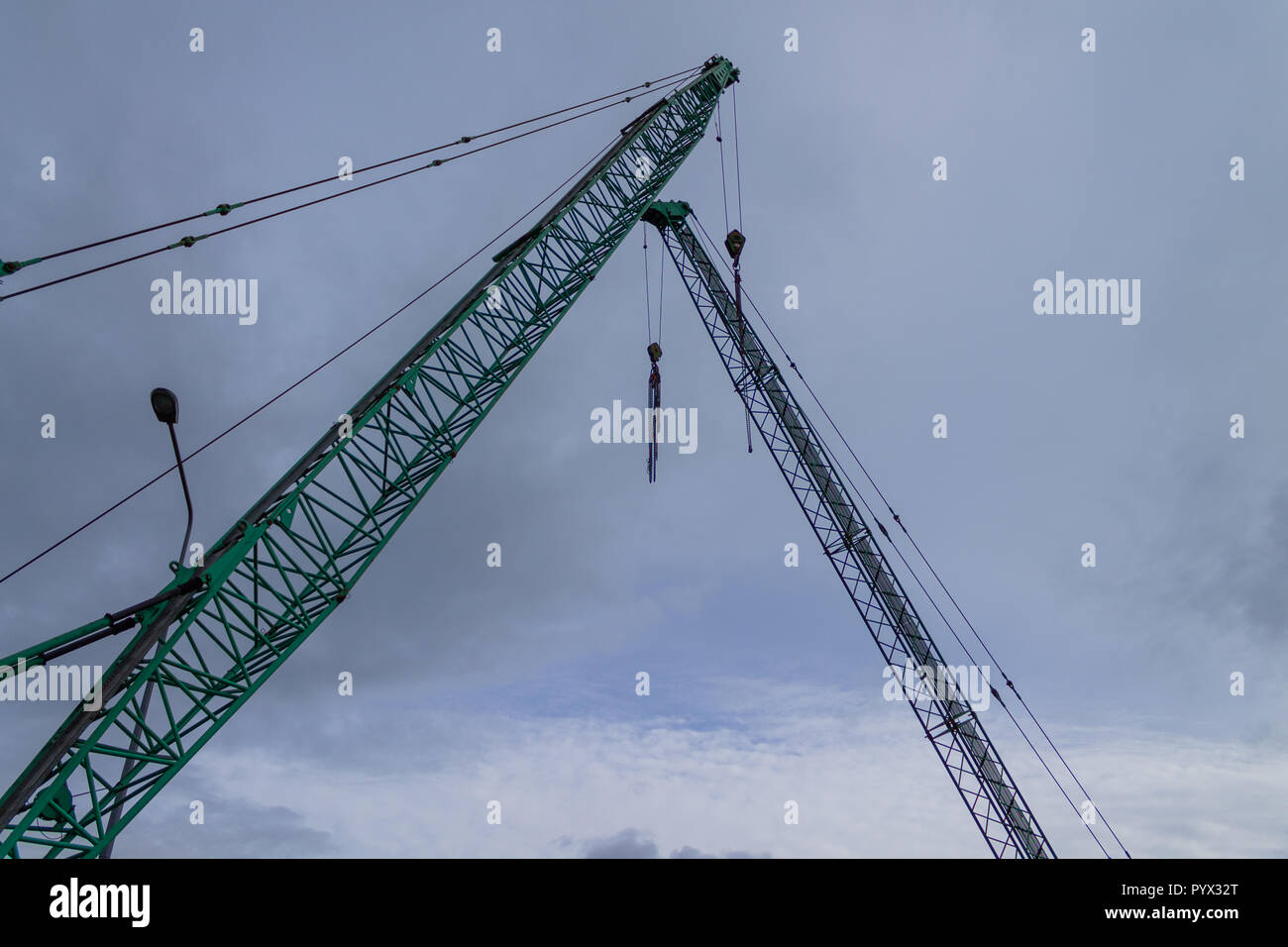 Kran Arme oder Ausleger oder Kran Kräne vor grauem stürmischen Himmel Silhouette Stockfoto