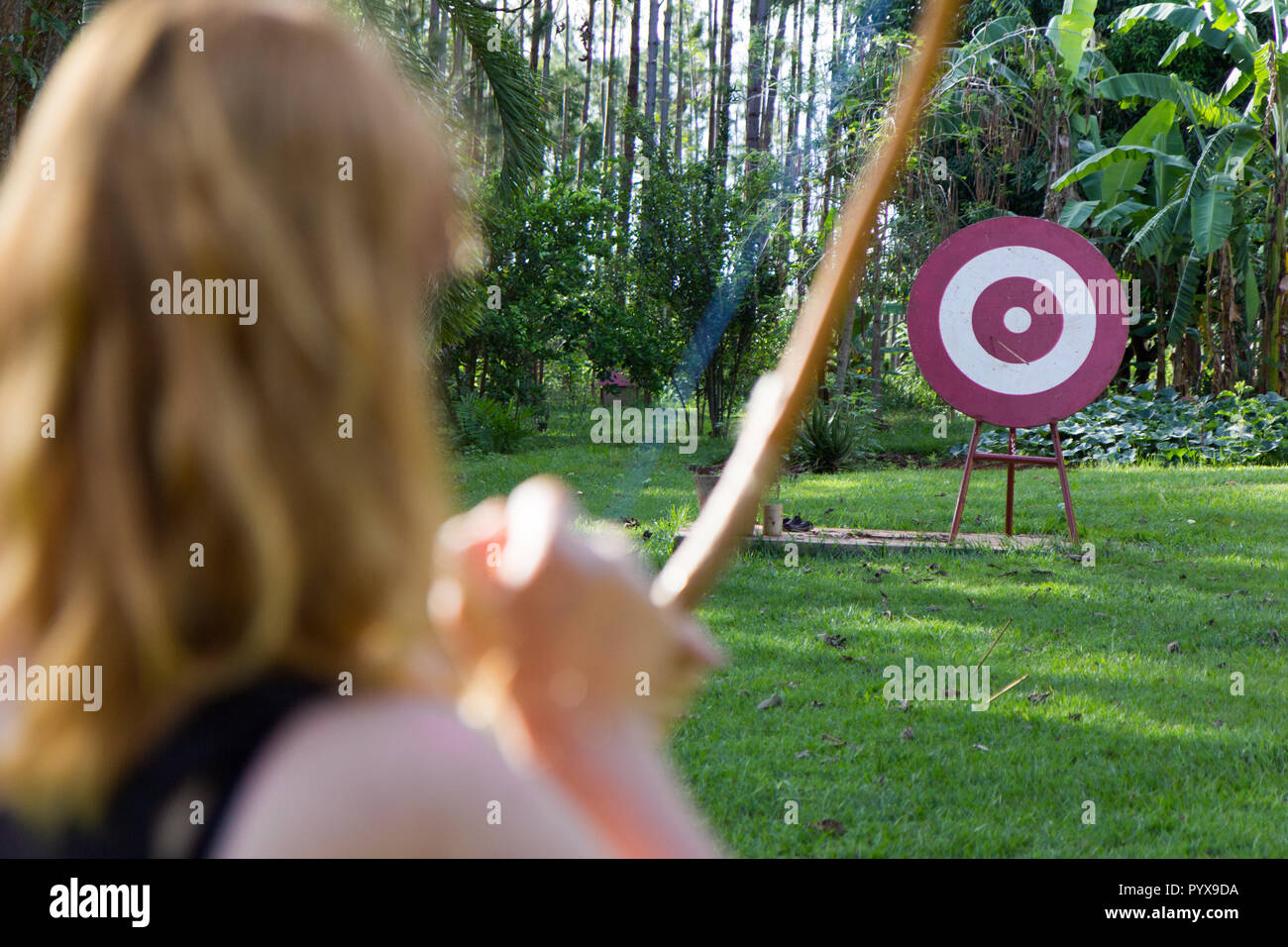 Eine Frau sport Bogenschützen schießt einen Pfeil mit Bogen an einer roten Holz- Ziel Stockfoto