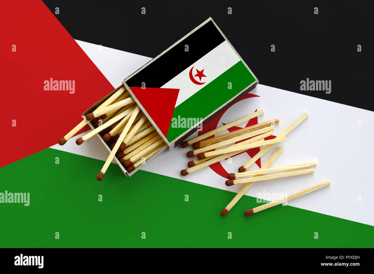 Westsahara Flagge ist auf einem offenen Streichholzschachtel, aus denen mehrere Treffer fallen gezeigt und liegt auf einer großen Fahne. Stockfoto