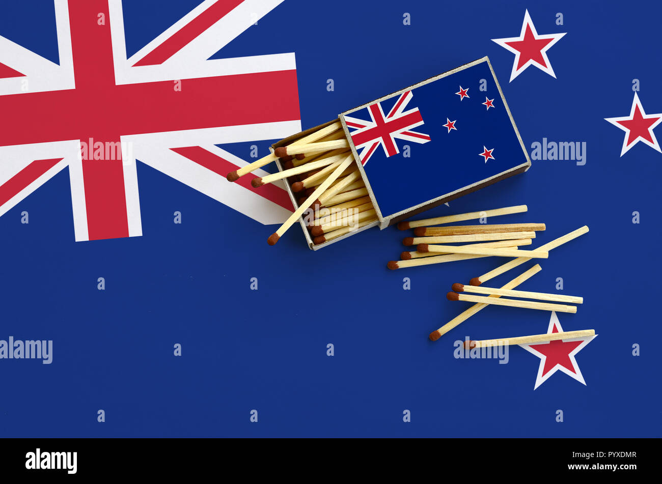 Neuseeland Flagge ist auf einem offenen Streichholzschachtel, aus denen mehrere Treffer fallen gezeigt und liegt auf einer großen Fahne. Stockfoto