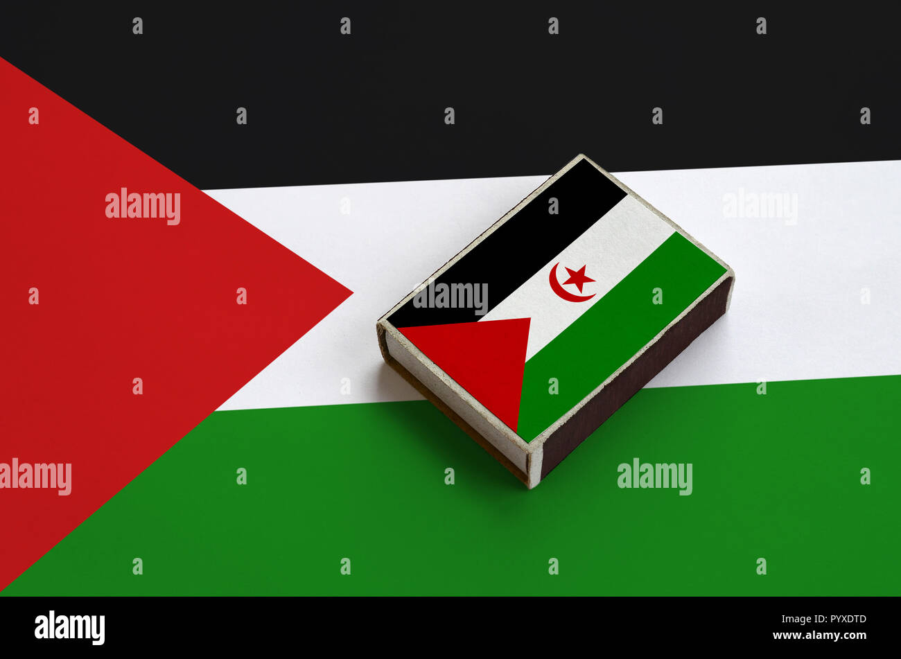 Westsahara Flagge ist abgebildet auf eine Streichholzschachtel, die auf eine grosse Fahne liegt. Stockfoto