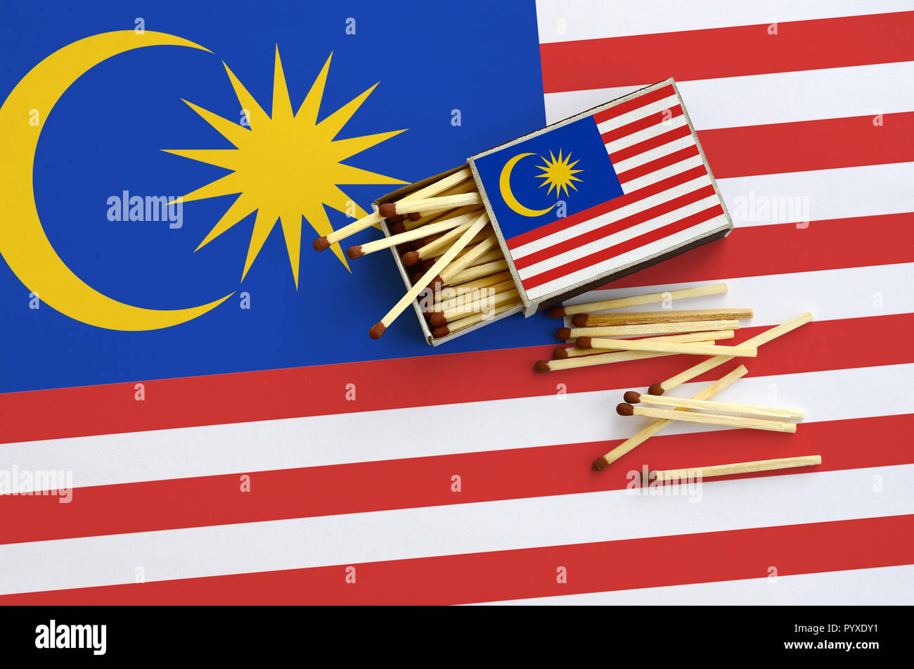 Malaysia Fahne ist auf einem offenen Streichholzschachtel, aus denen mehrere Treffer fallen gezeigt und liegt auf einer großen Fahne. Stockfoto