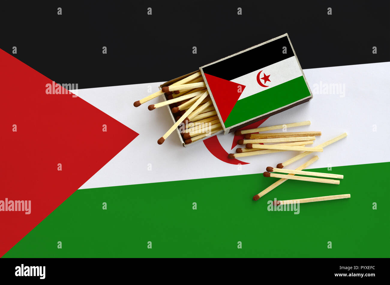 Westsahara Flagge ist auf einem offenen Streichholzschachtel, aus denen mehrere Treffer fallen gezeigt und liegt auf einer großen Fahne. Stockfoto