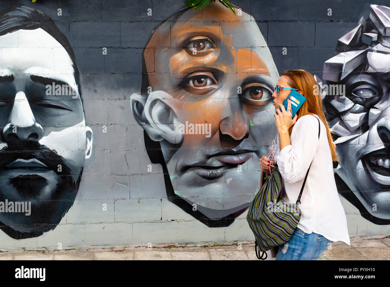 Frau Vergangenheit graffiti Köpfe wandern während auf Handy, Malaga, Andalusien, Spanien Stockfoto