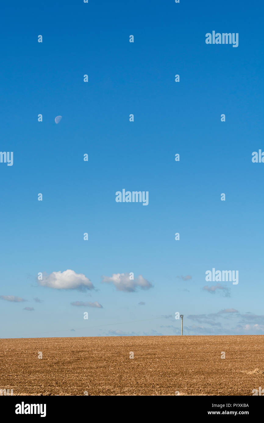 Vorbereitete Feld (nach dem Pflügen) mit blauen herbstlichen Himmel hinter - mit Mond. Gepflügte Erde. Stockfoto
