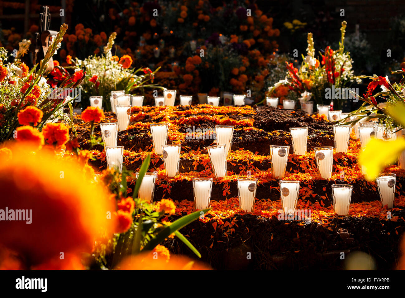 Schichten der Ringelblume Blüten und Votiv Kerzen schmücken die Patzcuaro, Michoacán Friedhof während der Tag der Toten, Mexiko. Stockfoto