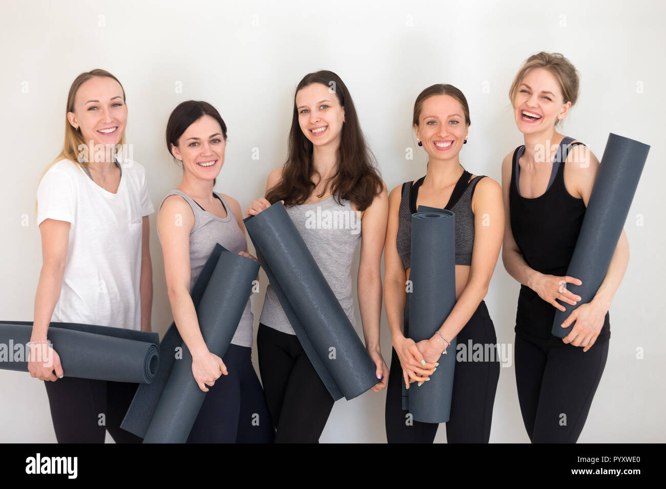 Gruppe von Frauen, die sich gerne sportlich Yogamatten stehen im Innenbereich Stockfoto