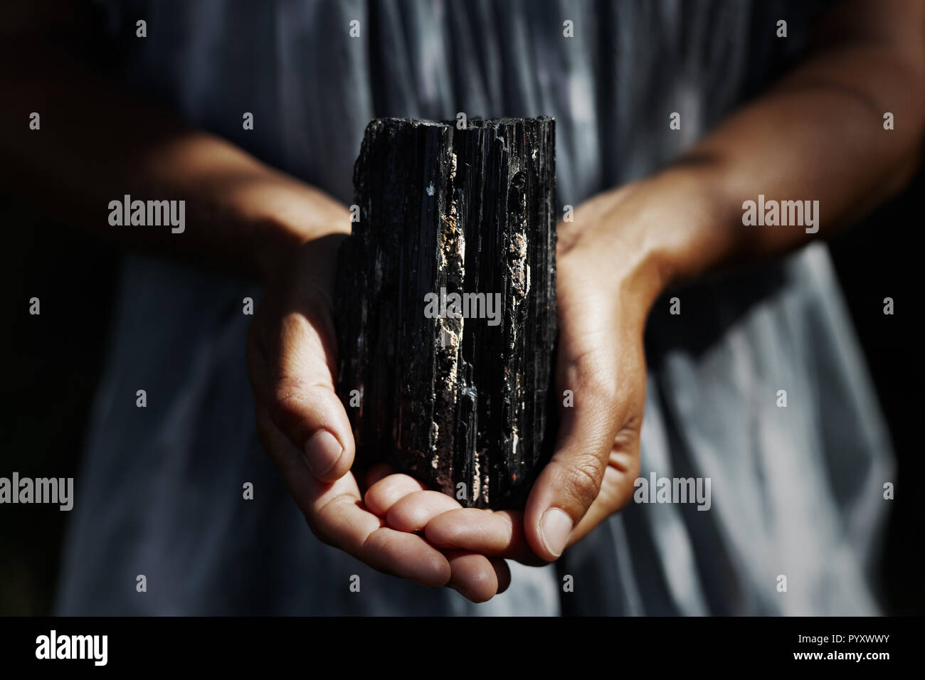 Woman's Hände, die Dunkle, kräftige schwarze Turmalin Kristall in Heilung Konzept Stockfoto