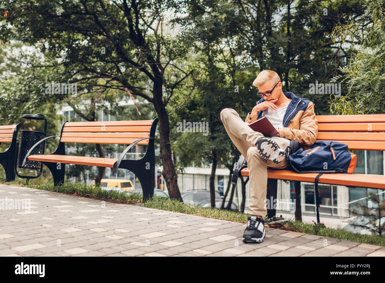 Student Mit Rucksack Lesen Buch Wandern Im Herbst Park Sitzt Auf Der Bank Man Studieren Im Freien Stockfotografie Alamy