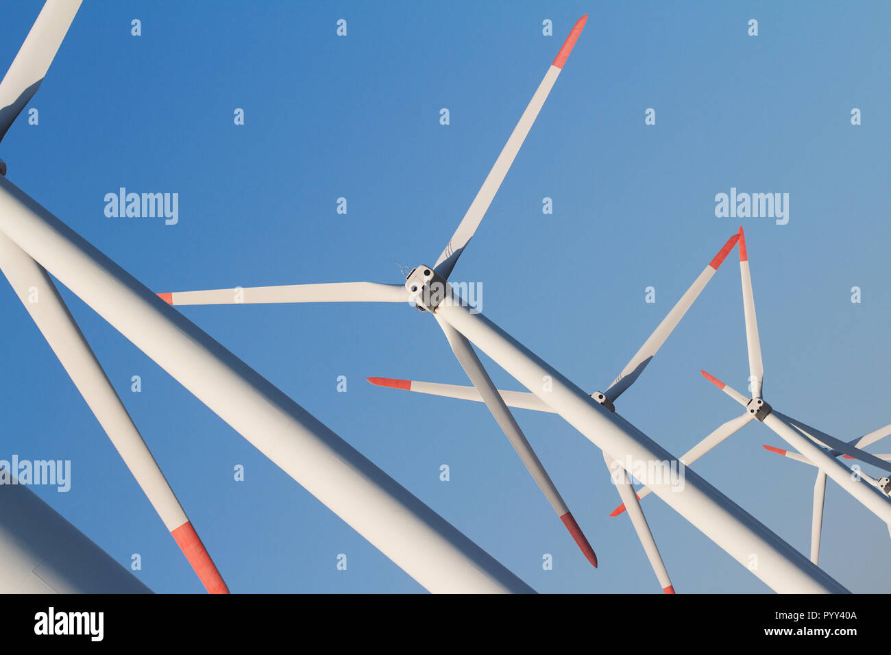 Horizontale gewinkelte Blick auf Zeile weiß äolischen Windenergieanlagen in einem Energie Farm gegen ein strahlend blauer Himmel Stockfoto
