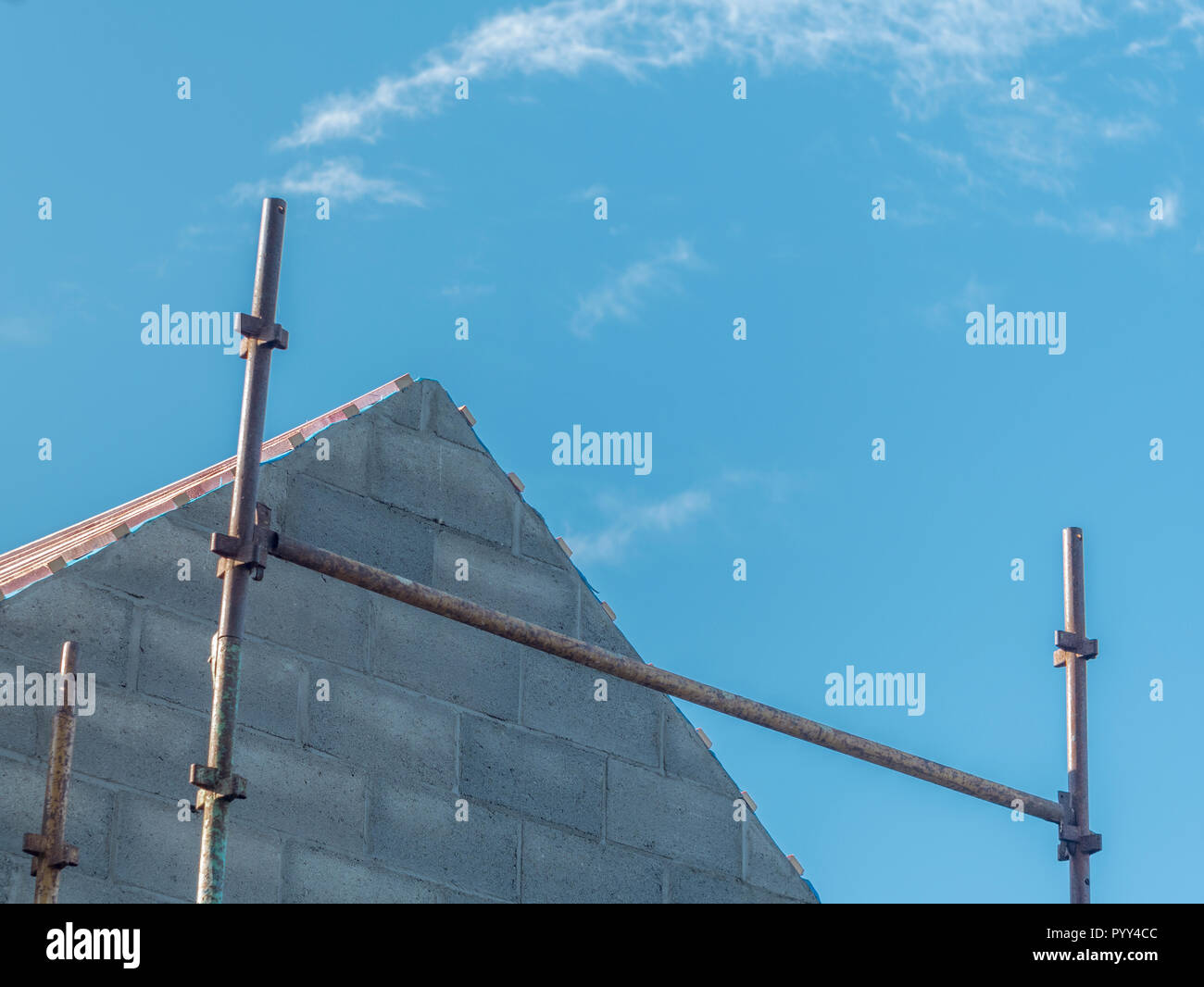 Giebelende eines neu gebauten Hauses mit sichtbarem Gerüst. Gegen den blauen Himmel. Für den britischen Baugewerbe. Stockfoto