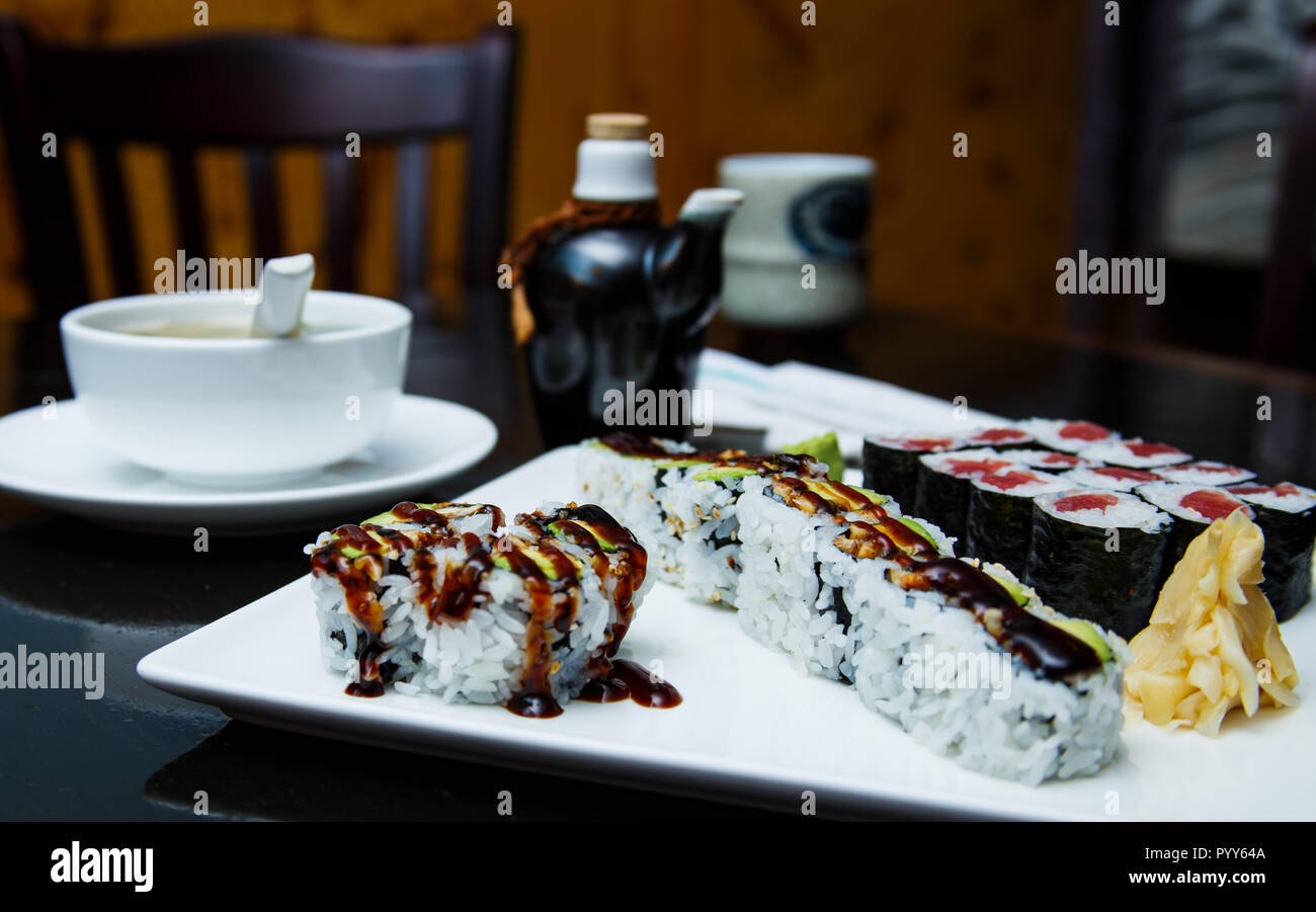 Frisches Sushi rollen, Misosuppe und ein Glas Soja Sauce auf einen dunklen Tisch. Stockfoto