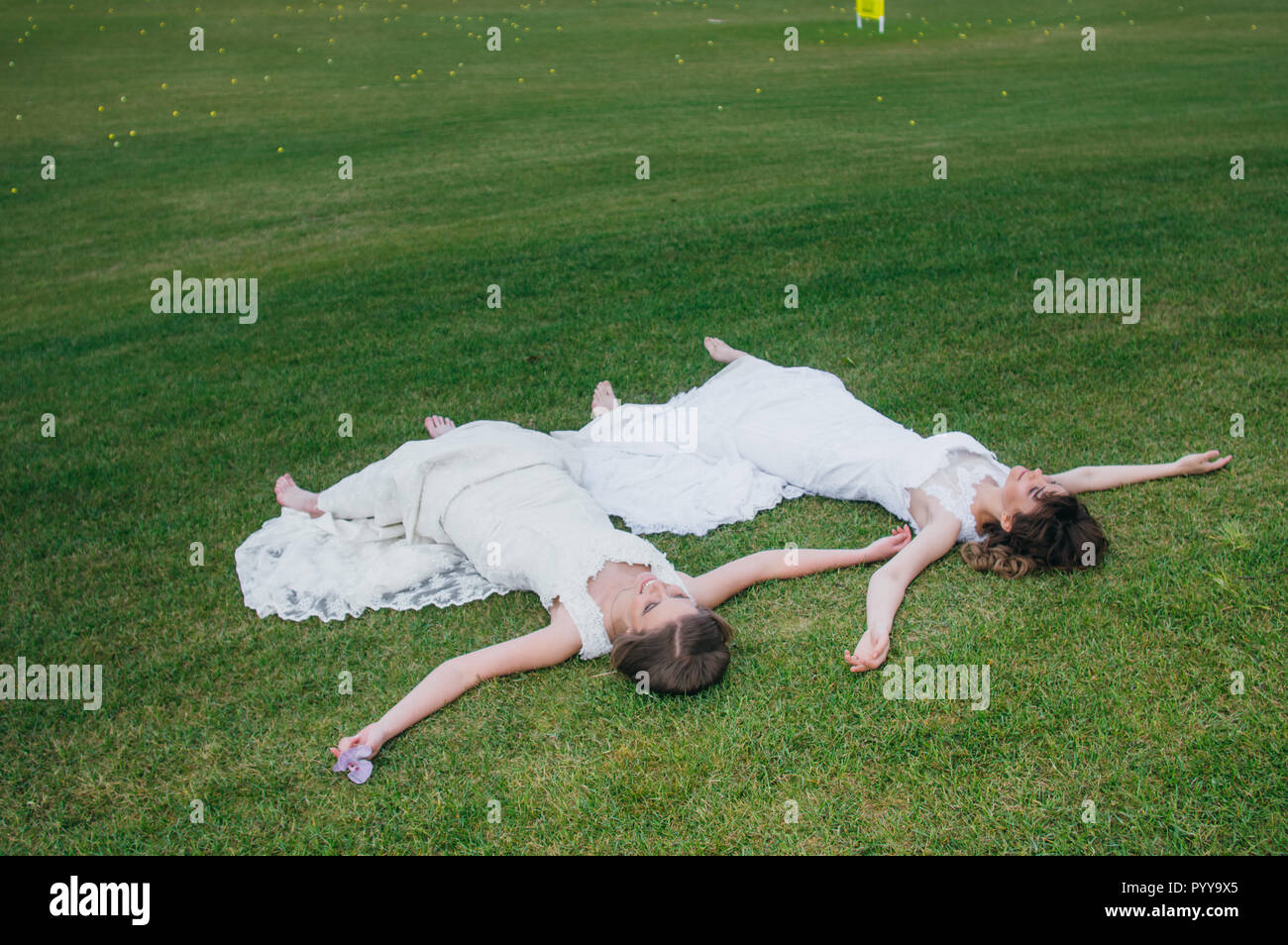 Zwei schöne Bräute liegen auf dem grünen Feld des Golf Club Stockfoto