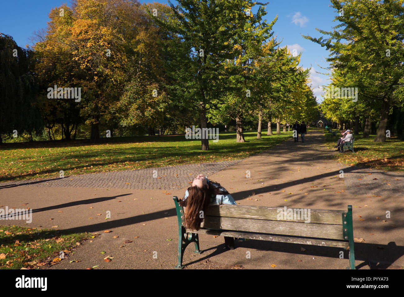 Frau sitzt auf der Parkbank mit Kopf zurück in Bute Park Cardiff Wales geworfen Stockfoto