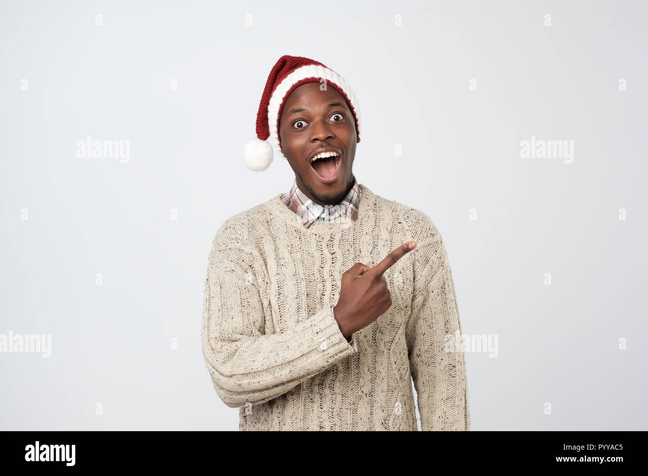 Schönen afrikanischen Mann in rot weihnachten cap Pointing Finger und Kamera. Stockfoto