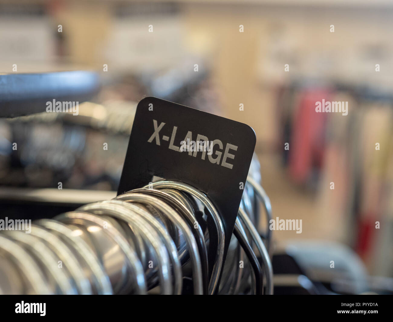 X-Groß Extra Groß Kleidung Abschnitt Zeichen auf Stahl hängenden Rack mit Kleiderbügel im Kaufhaus Stockfoto