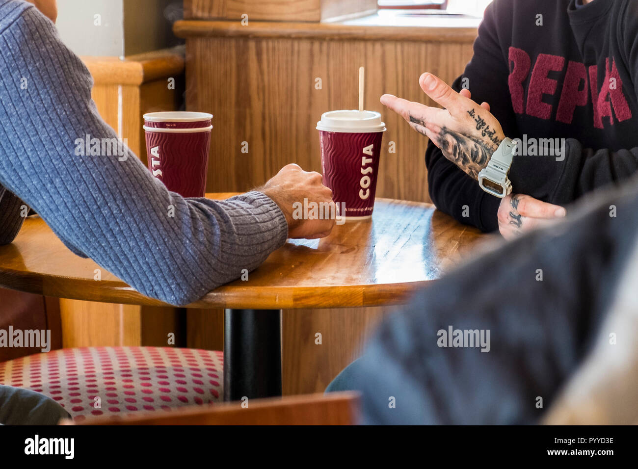 Männer plaudern und Geselligkeit bei einem Kaffee in einem Costa Coffee Shop. Stockfoto