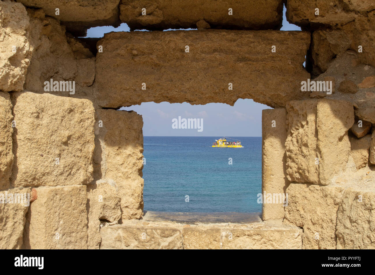 Eine kleine Kreuzfahrt Schiff durch eine Lücke in den mittelalterlichen Mauern der alten Stadt von Rhodos Griechenland gesehen. Die Altstadt von Rhodos ist ein Weltkulturerbe. Stockfoto
