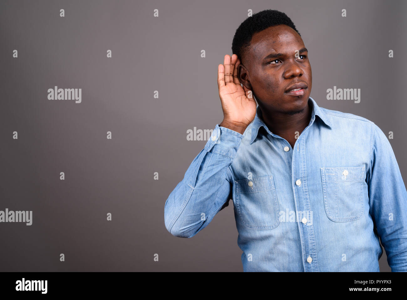 Junge afrikanische Mann tragen Jeanshemd gegen grauer Hintergrund Stockfoto