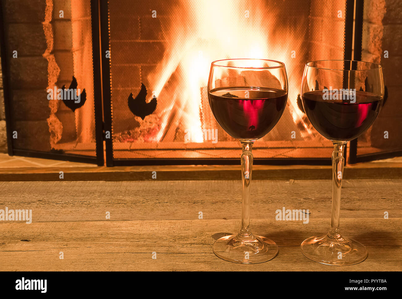 Ruhige Szene vor dem gemütlichen Kamin, mit zwei Gläsern Rotwein, im Landhaus, im Winter Urlaub. Stockfoto