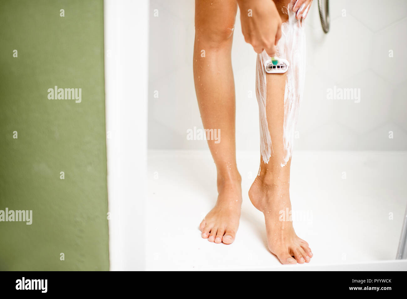 Frau rasieren ihre Beine mit Razor und Schaum in der Duschkabine Stockfoto