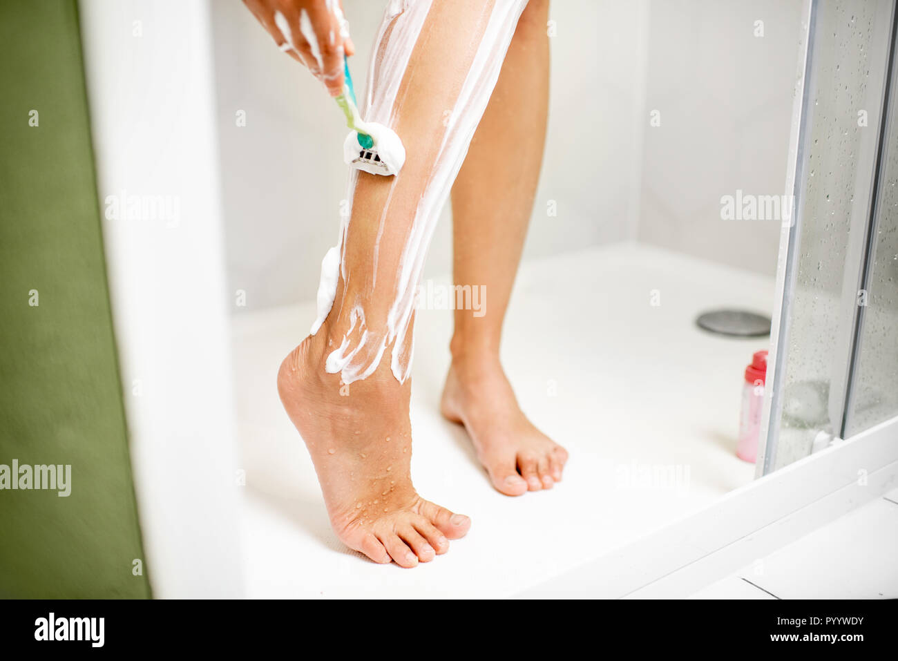 Frau rasieren ihre Beine mit Razor und Schaum in der Duschkabine Stockfoto