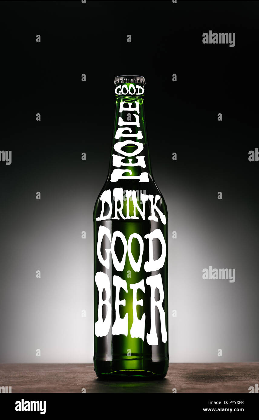 Flasche Bier auf dunkelgrauem Hintergrund mit 'guten Menschen trinken gutes Bier' Inspiration Stockfoto