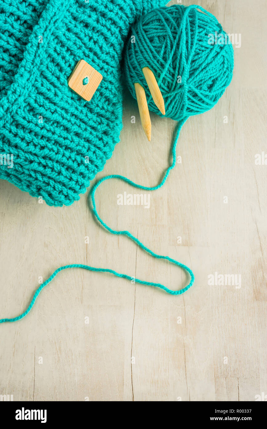 Türkis Stricken arbeiten mit Stricknadeln und einem Wollknäuel auf einer hölzernen Oberfläche Stockfoto