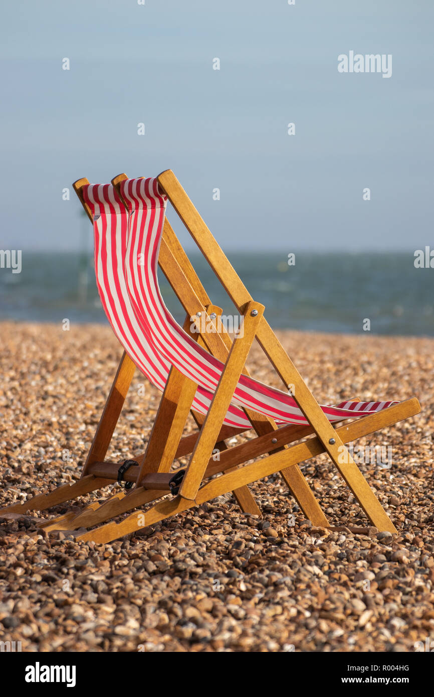 Rote und weiße Strand Liegestühle auf einer britischen Pebble Beach Stockfoto