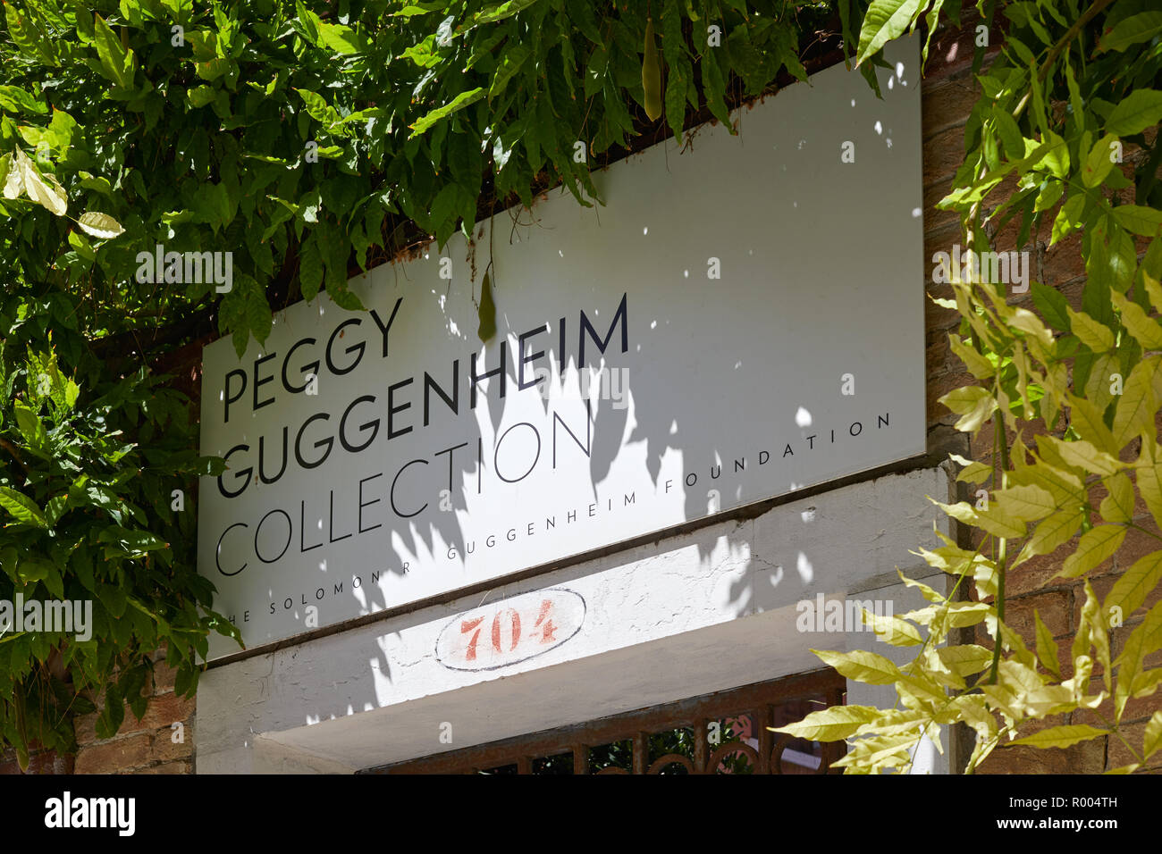Venedig, Italien - 14 AUGUST 2017: Peggy Guggenheim Collection Museum anmelden, indem grüne Blätter in Venedig in einem sonnigen Tag umgeben, Italien Stockfoto