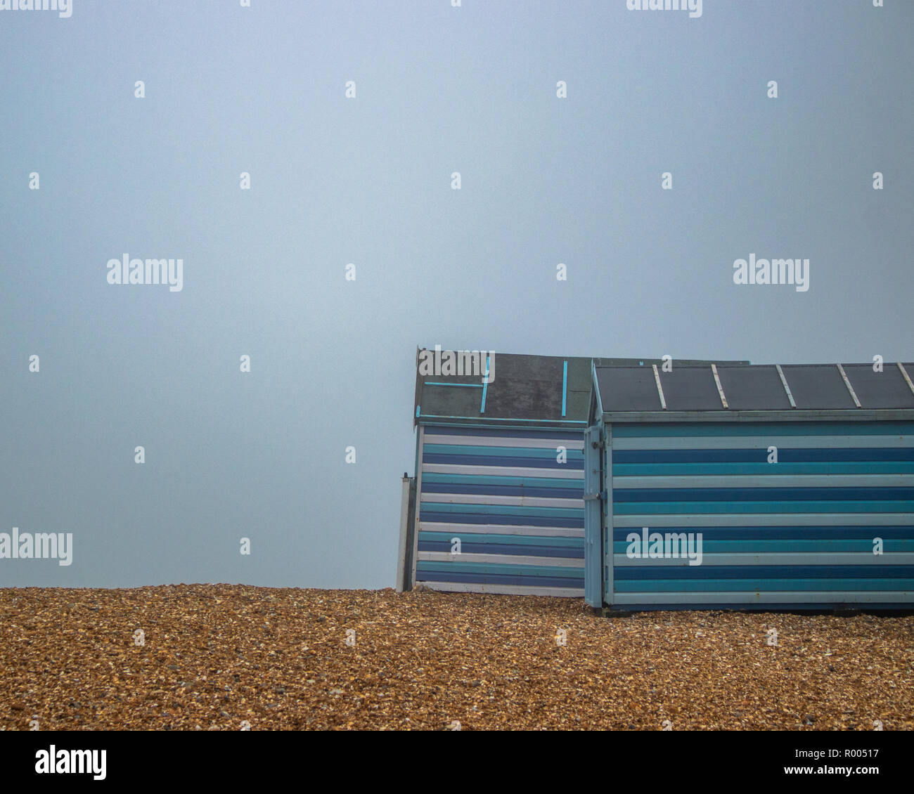 Blau und Weiß Gestreifte britischen Strand Hütten im Nebel auf einem Kieselstrand Stockfoto