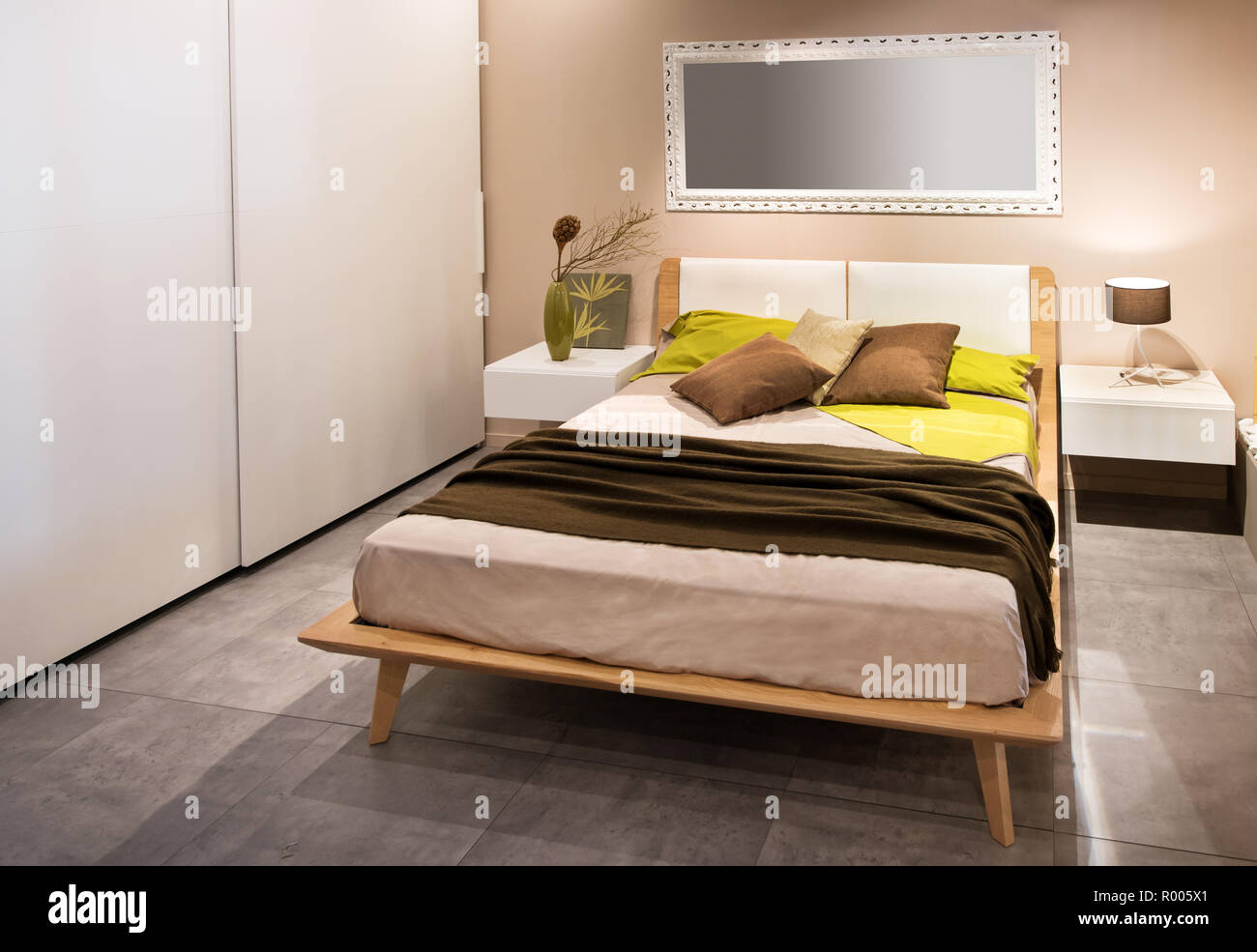Modernes Schlafzimmer mit Doppelbett und im skandinavischen Stil seite Schränke in Beige und Grau gehaltene Einrichtung mit gelben Akzent Kissen auf dem divan Stockfoto