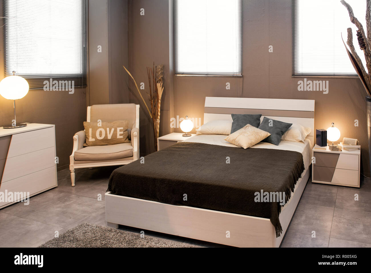 Romantische braun luxuriöse Schlafzimmer mit Sofa Bett und Stuhl mit Liebe Kissen mit runden Lampen beleuchtet Stockfoto