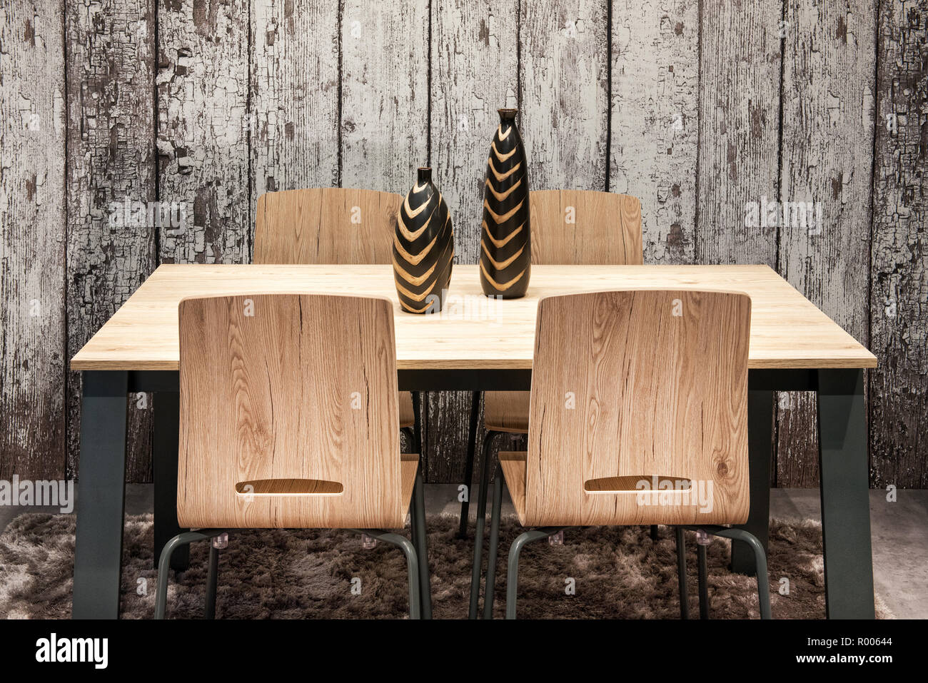 Moderne Holz- Ess- oder Küchentisch und Stühle mit stilvollen Keramik Vasen vor einem rustikalem Holz Wand Stockfoto