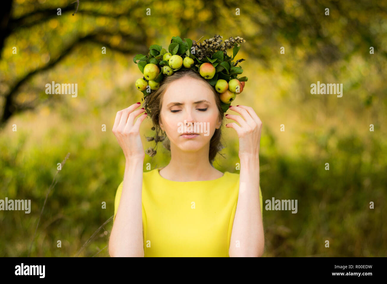 Porträt der jungen Frau in Apple Garten mit Kranz auf dem Kopf Stockfoto