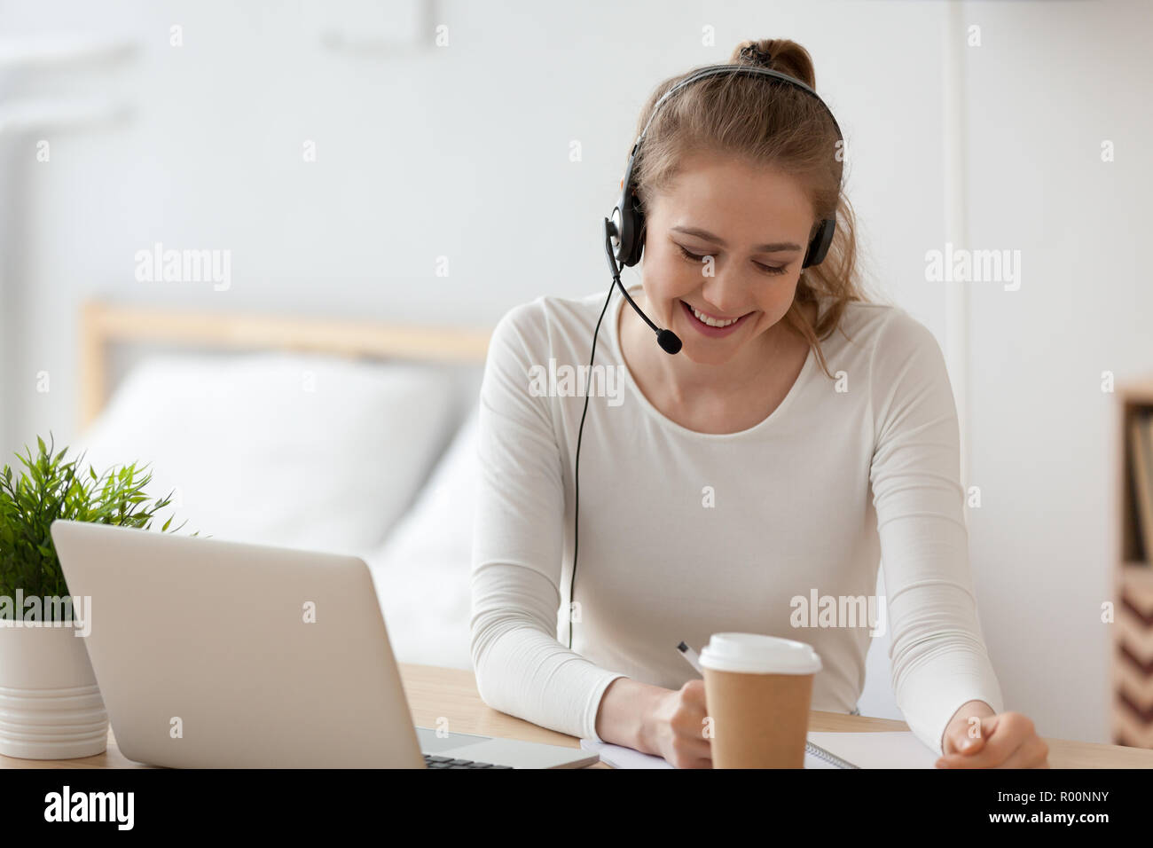 Fröhliche Frau das Headset mit Mikrofon arbeiten im Innenbereich Stockfoto