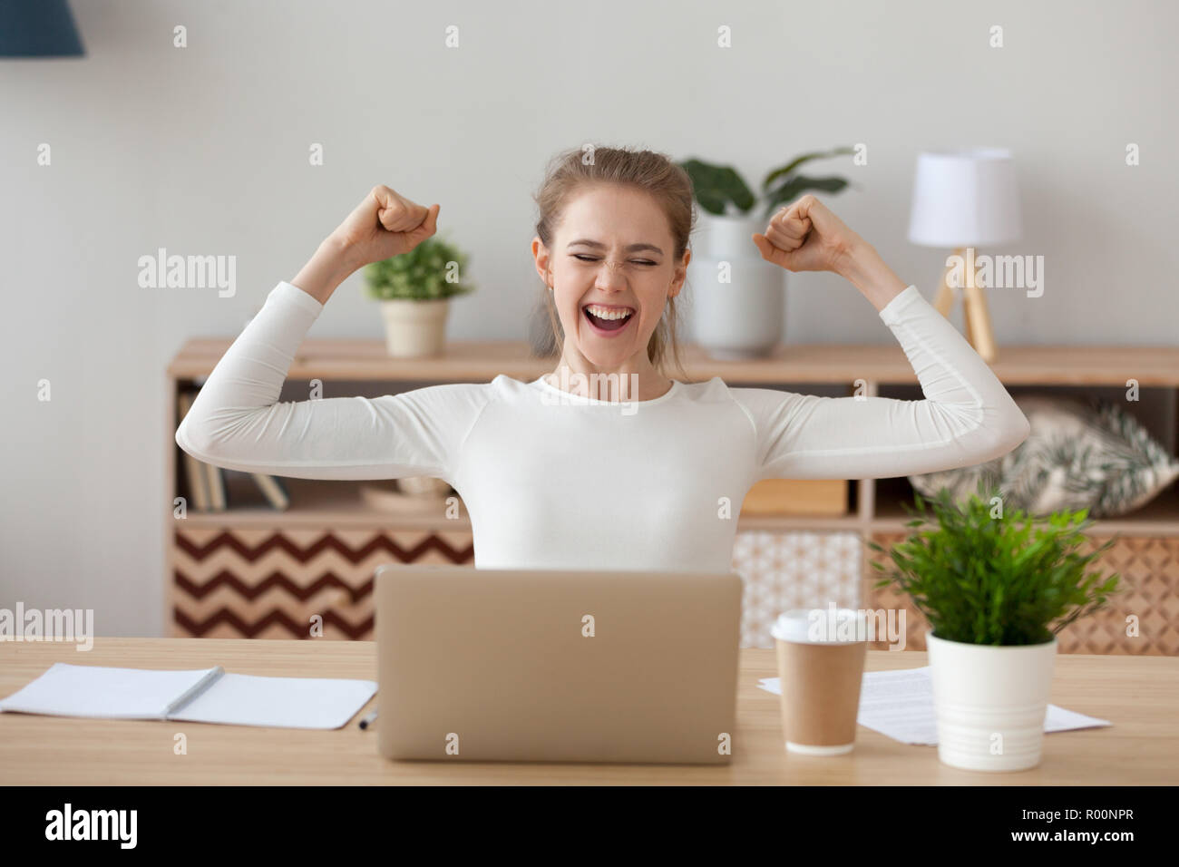Aufgeregt Frau fühlt sich glücklich am Schreibtisch sitzen Stockfoto